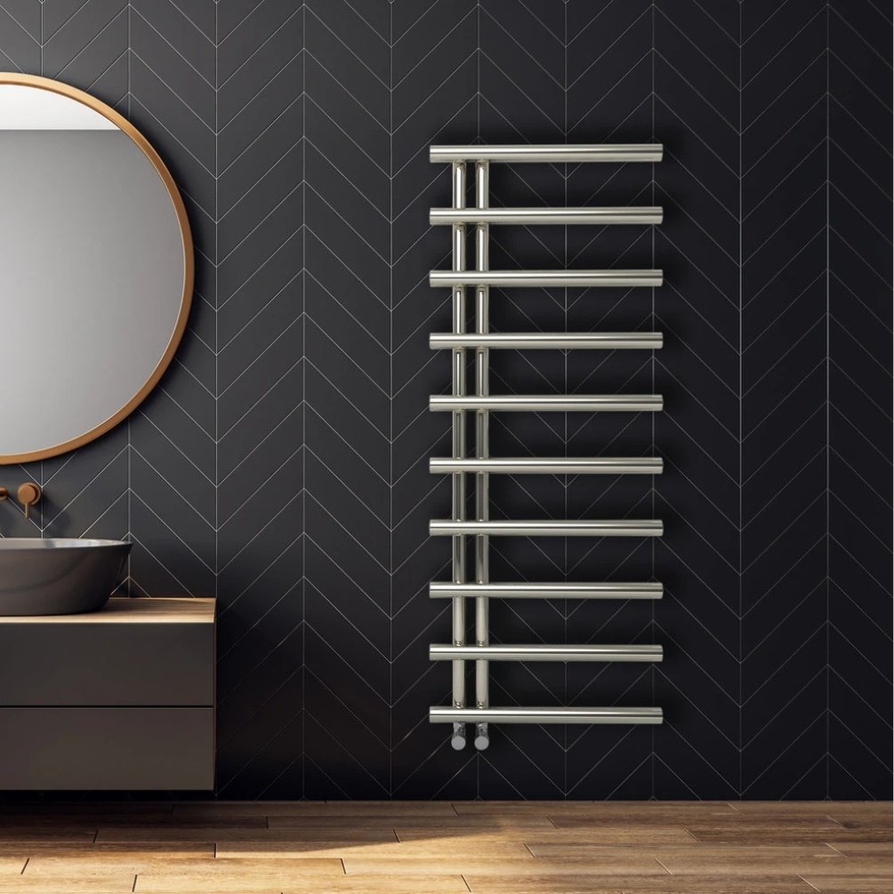 Lifestlye image of the Radox Orchid 1265mm x 500mm Stainless Steel Heated Towel Radiator mounted on a black bathroom wall, next to a round mirror and countertop vanity unit & basin